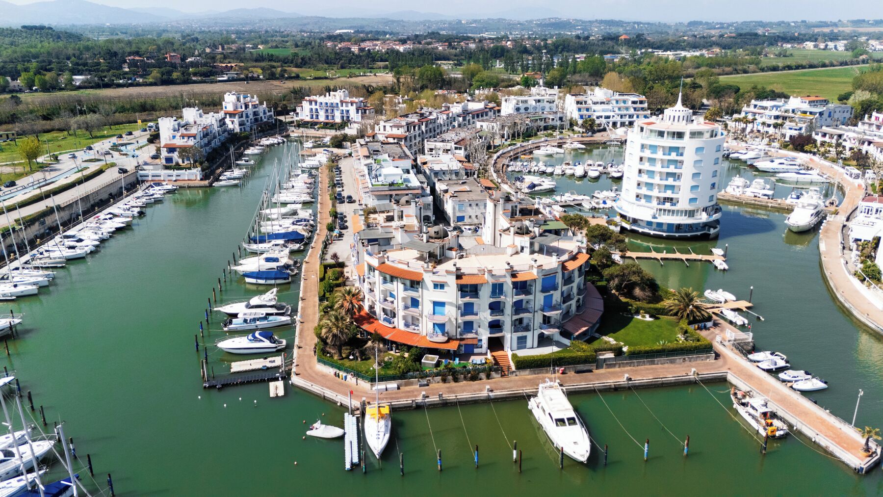 A marina with multiple boats docked, surrounded by residential buildings with balconies.