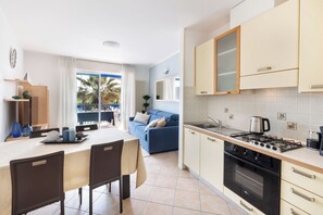 A modern kitchen with a gas stove, oven, and a dining area with a table and chairs.