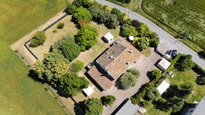 An aerial view of a property with a central building surrounded by trees and a road.