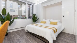 Ein modernes Hotelzimmer mit Bett, Fenster und Blick auf die Straße.