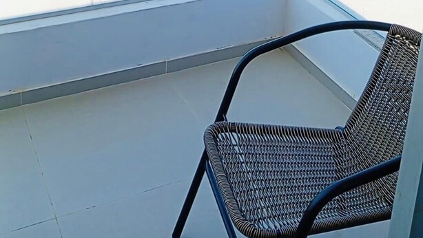 Un balcone con vista sul mare, una sedia e un parapetto in vetro.