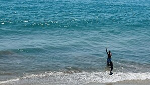 Una spiaggia con barche sull'acqua e una persona che si trova in acqua bassa.