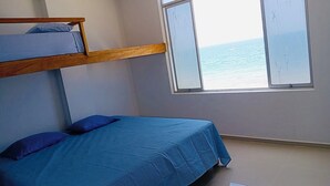 Una stanza con un letto a castello, un letto singolo e una finestra vista mare.