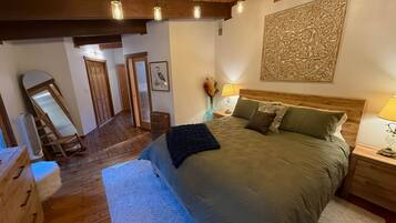 A bedroom with a large bed, wooden headboard, and a decorative wall piece.