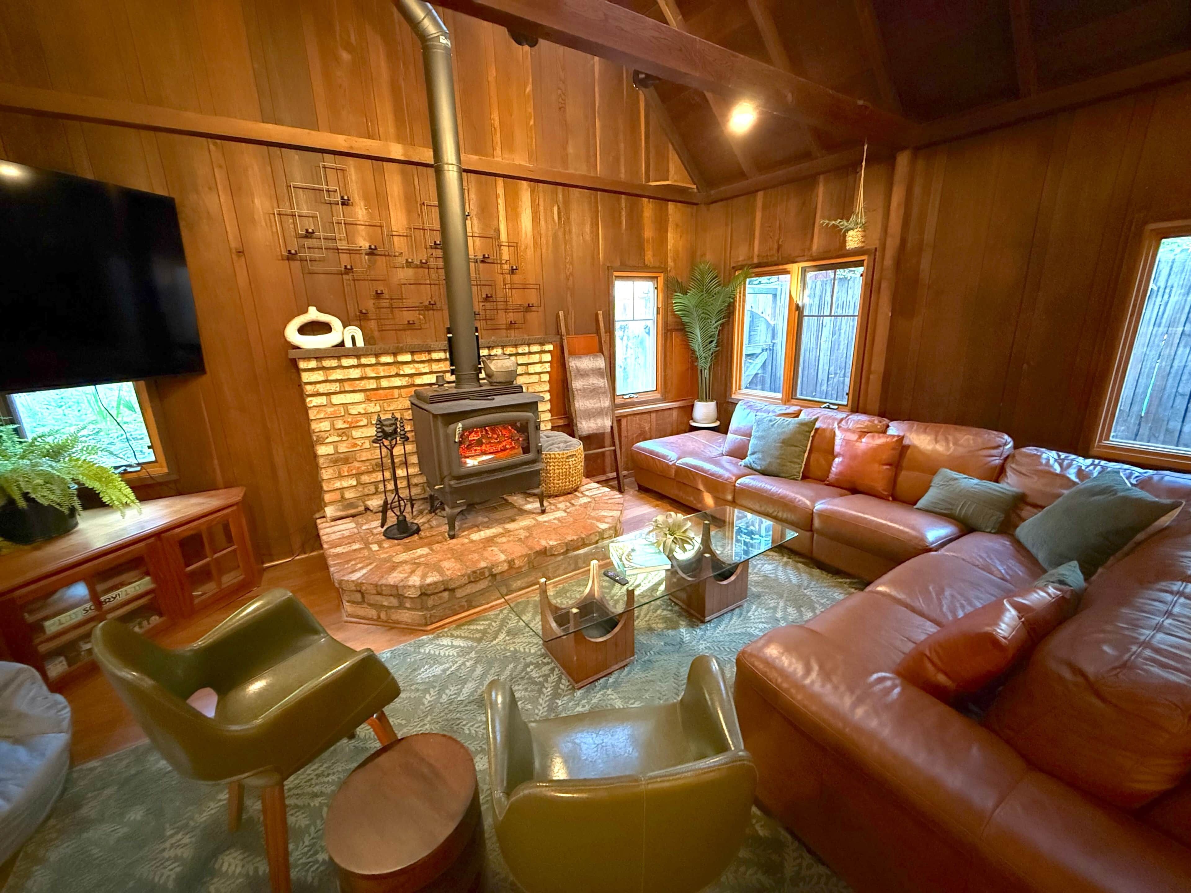 A cozy living room with a fireplace, leather sofa, and a flat-screen TV.