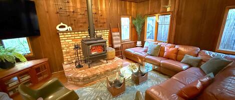 A cozy living room with a fireplace, leather sofa, and a flat-screen TV.