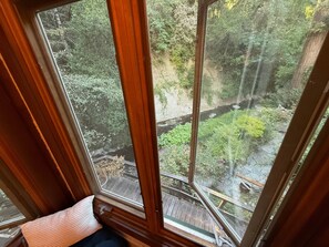 A room with a large window overlooking a wooden deck and a garden.