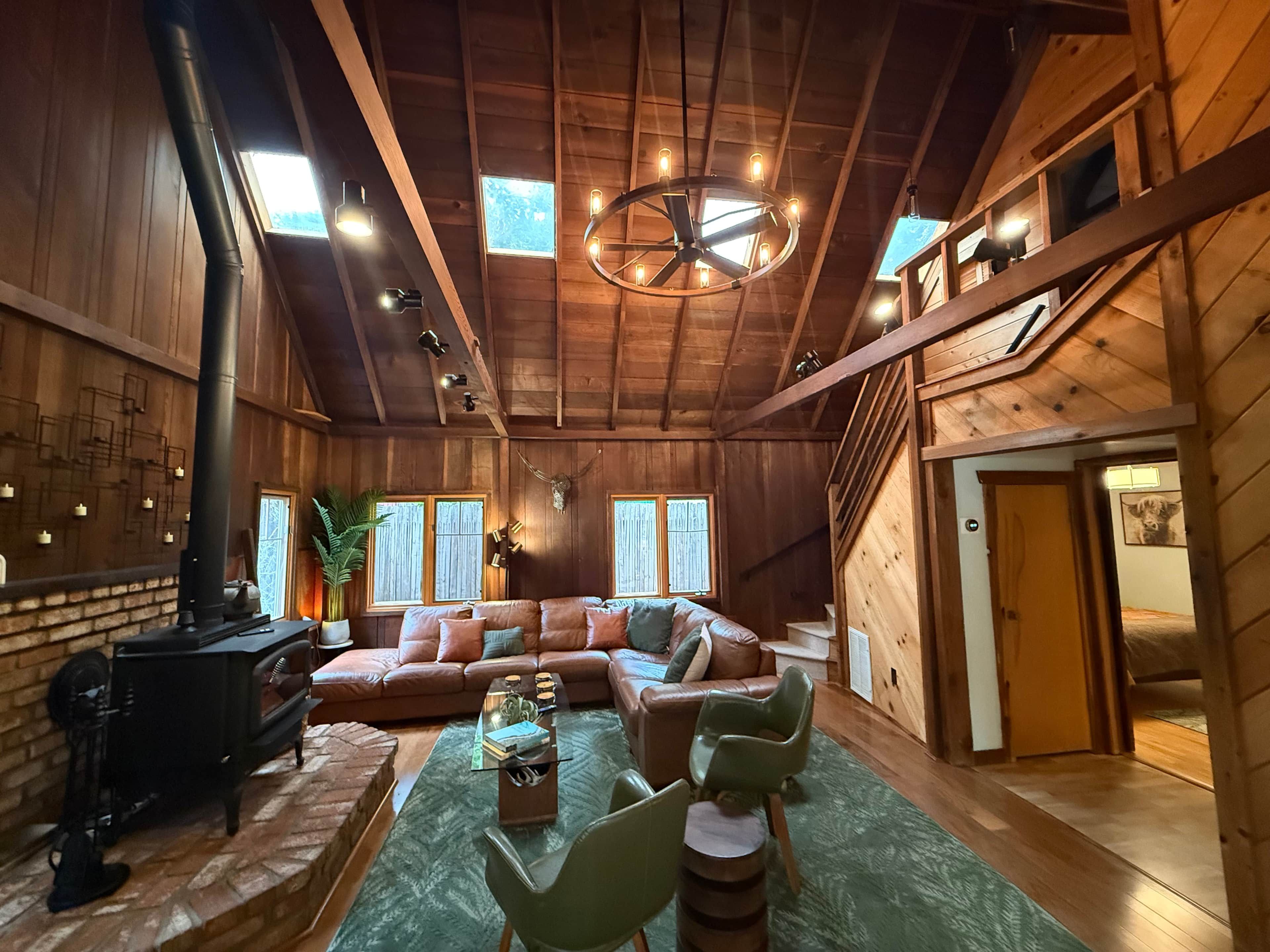 A cozy cabin interior with a fireplace, a sectional sofa, and a dining area.