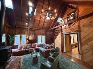 A spacious living area with a large L-shaped sofa, a glass coffee table, and a fireplace.