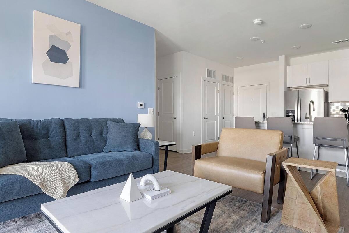 A modern living room with a blue sofa, a beige armchair, and a white coffee table.