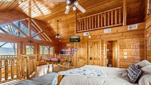 Ein Holzblockbau-Interieur mit einem Bett, einem Billardtisch und einem Balkon.