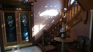 A staircase with wooden railings, a round table with a floral pattern, and a chair. - Spacious Victorian Mansion with 8-bedroom in marvelous Denver with AC (Denver)