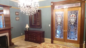A room with a chandelier, a wooden door with stained glass, a fireplace, and a dresser. - Spacious Victorian Mansion with 8-bedroom in marvelous Denver with AC (Denver)