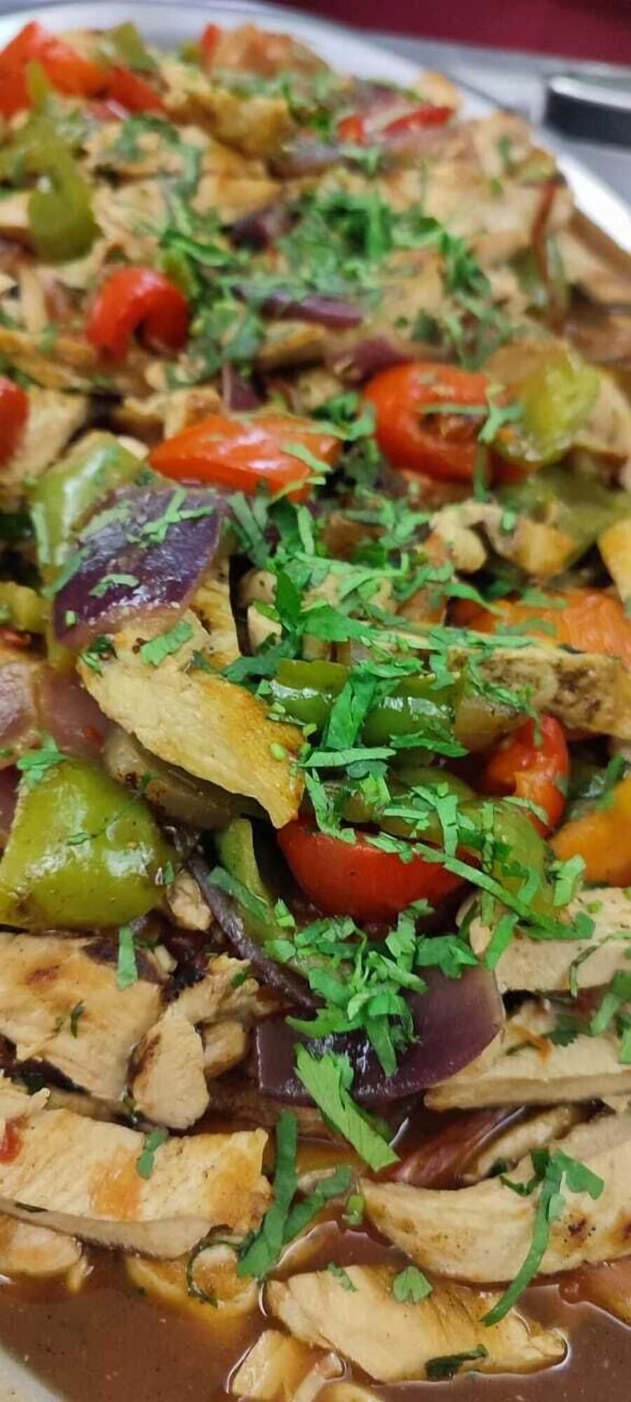 A dish with various vegetables and chicken, garnished with herbs.
