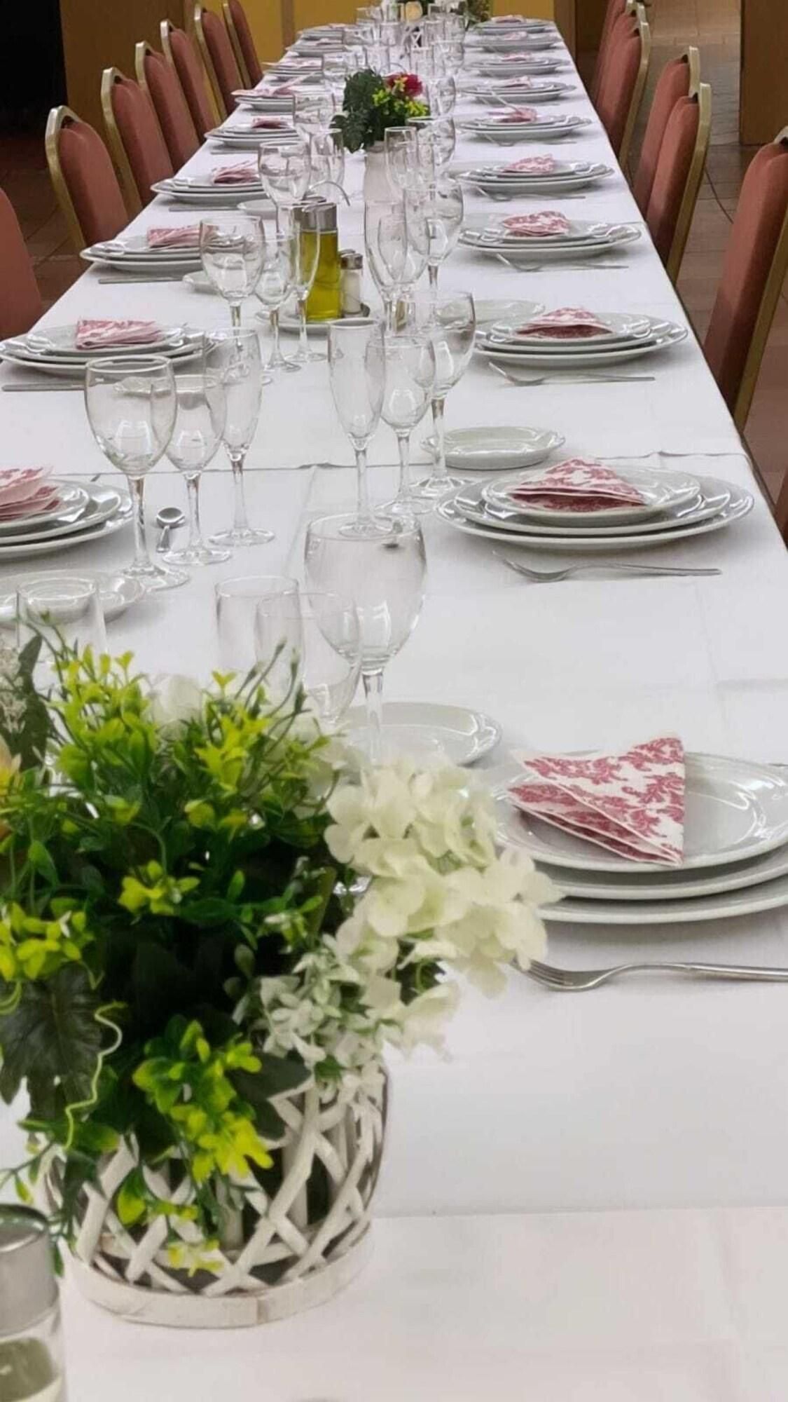 Een lange eettafel gedekt met borden, glazen en een middelpunt.