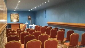 A conference room with rows of chairs, a podium, and a blue wall.
