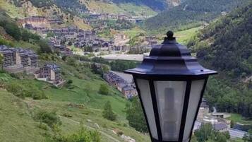 A scenic view of a mountainous landscape with a village and a black street lamp in the foreground.