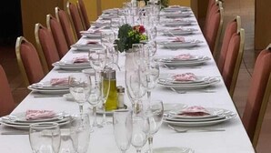 A long dining table set with plates, glasses, and a centerpiece.