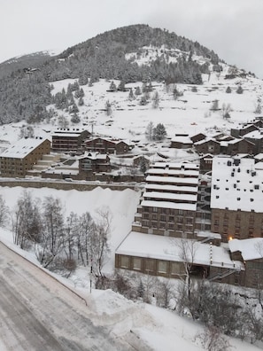 A snow-covered residential area with multi-story buildings, some with balconies, and a hilly backdrop. - Ransol (Ransol)