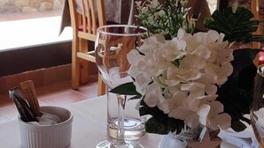 A dining table set with white tablecloth, a vase of white flowers, and a glass of water.
