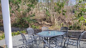 Un área de estar al aire libre con una mesa y sillas, rodeada de grava y vegetación.