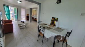 Un comedor con una mesa dispuesta para cuatro personas, un sofá y una cama al fondo.