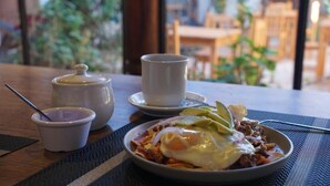 A dining table with a plate of food, a cup, and a small container. - Arles ByB Cafe (San Cristóbal de las Casas)