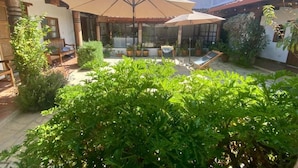 A patio area with outdoor seating, potted plants, and a pergola structure. - Arles ByB Cafe (San Cristóbal de las Casas)