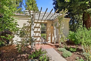 A garden with a pergola, a pathway, and a building with a door. - Atherton Garden ADU in Silicon Valley (Atherton)