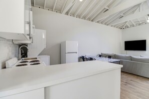 A modern kitchen with white cabinetry, a built-in stove, and a dining area with a table and chairs. - Atherton Garden ADU in Silicon Valley (Atherton)