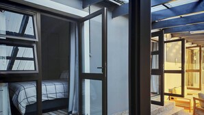A room with a bed, a window, and a door leading to a balcony. - Room-courtyard Room With Shared Bathroom (Cape Town)