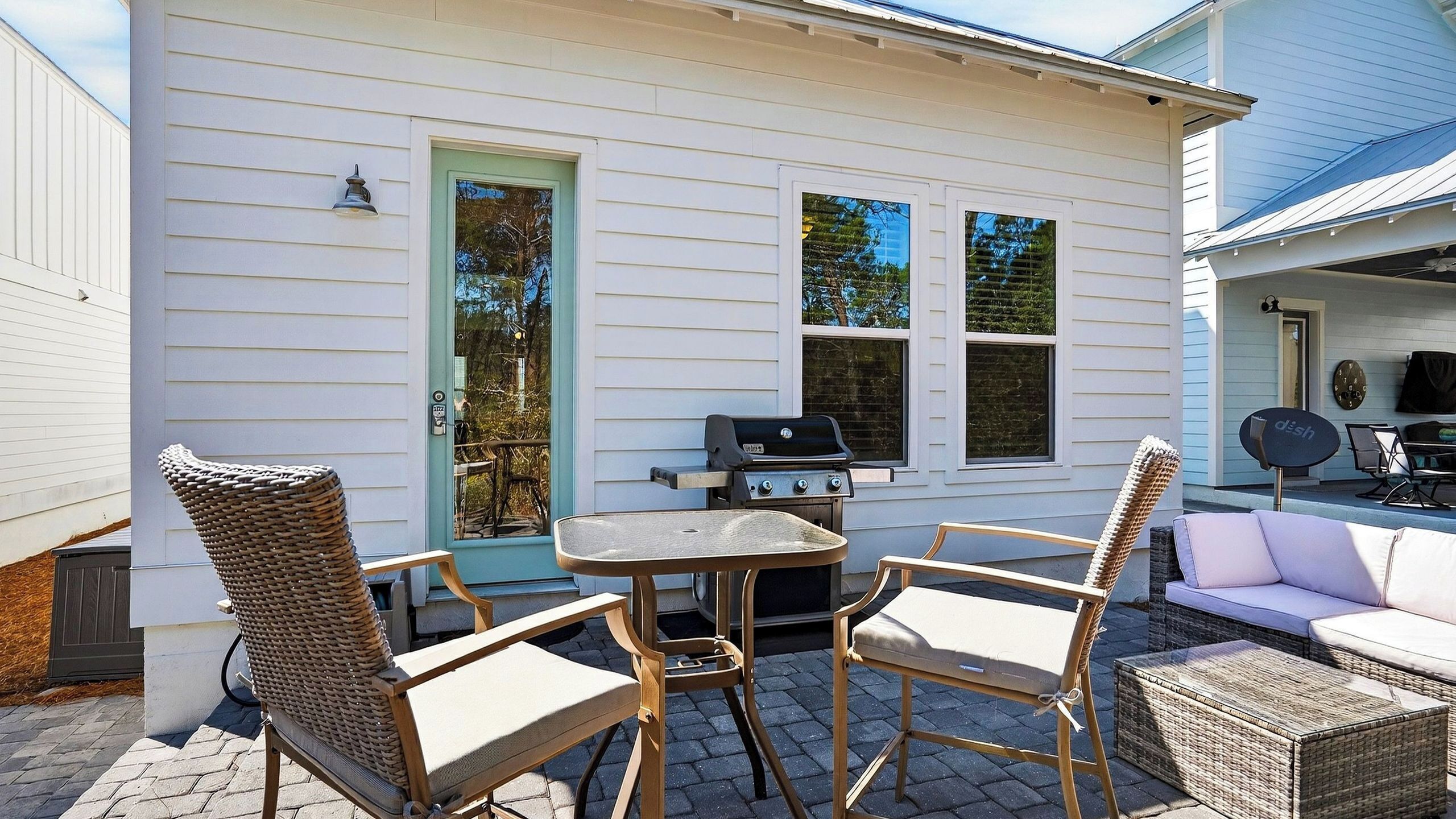 A patio with wicker furniture, a grill, and a white couch.