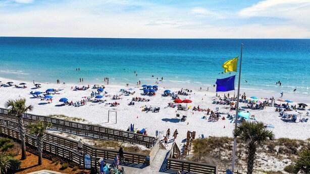 A beach with a wooden boardwalk, beach umbrellas, and a flag. - Southern Dreams on 30A by Avantstay Pool + Outdoor Lounge + Golf Cart Access Minutes to the Beach (Santa Rosa Beach)