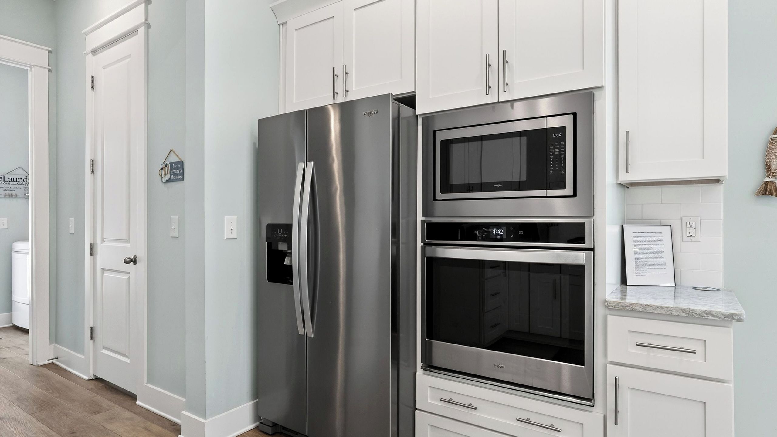 A kitchen with stainless steel appliances, white cabinetry, and a water dispenser.