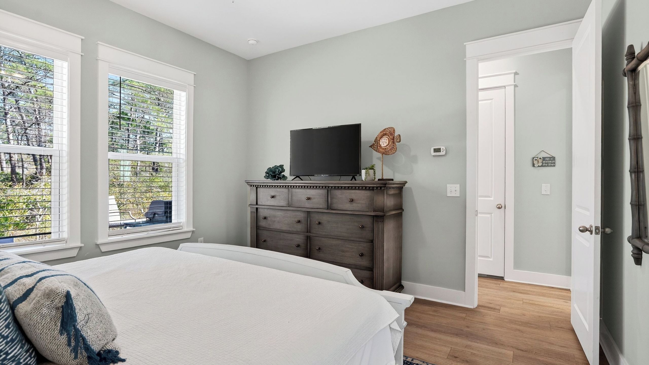 A bedroom with a bed, a dresser, a television, and a door.