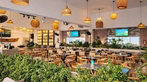 A spacious restaurant with wicker pendant lighting, multiple seating areas, and a television screen. - Ocean View and Direct Beach in Pozos Colorados (Santa Marta)
