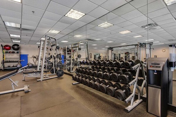 A gym with weightlifting equipment, a water dispenser, and a mirrored wall. - 🦩Book Me Baby! The Silver Lining at Silver Shells🦩 (Destin)