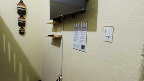 Ein Zimmer mit flachbildfernseher an der Wand, einem fest installierten Telefon, einer Steckdose und einem Willkommensschild.