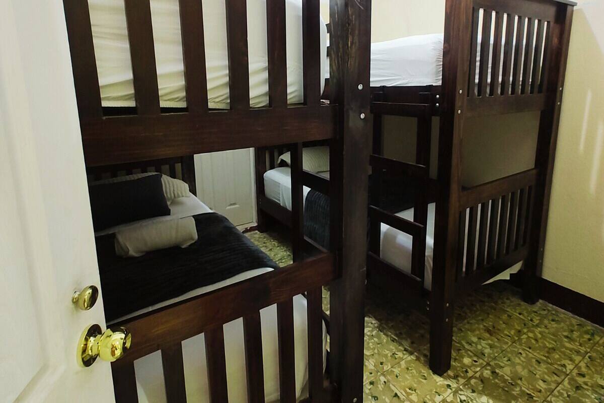 A room with bunk beds, a door with a brass handle, and patterned floor tiles.