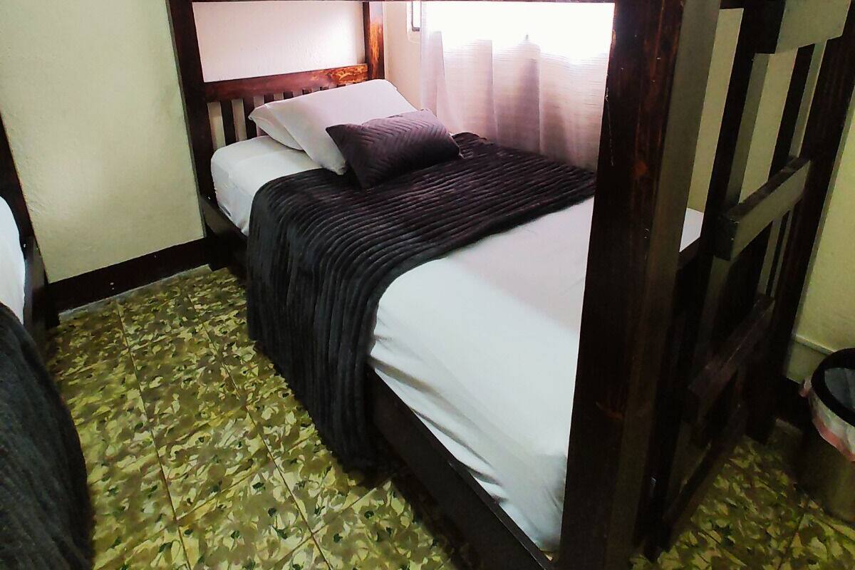 A bunk bed room with a wooden headboard, a bed with white bedding, and a patterned floor.