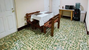 Ein kleiner Raum mit Esstisch, Stühlen, einer Mikrowelle und einem Wasserspender.