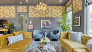 A modern living room with a sofa set, two armchairs, a coffee table with flowers, and a large window with a view. - The Bloom House & Cosmic Cowgirl by Avantstay Sleeps 17 + 2 Units Gym + Rooftop + Skyline Views (Nashville)