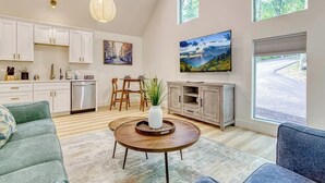 Una sala moderna con comedor, cocina y ventanas amplias.