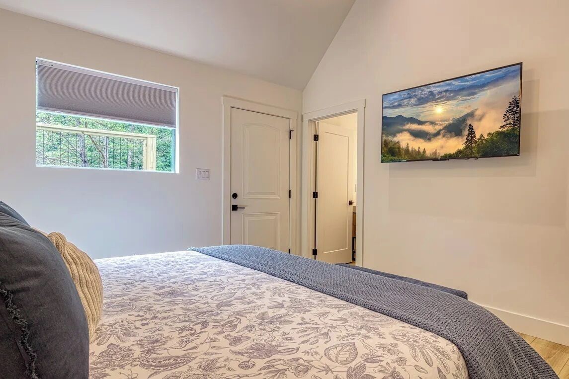 Un dormitorio con una cama, una ventana, una puerta y un cuadro en la pared.