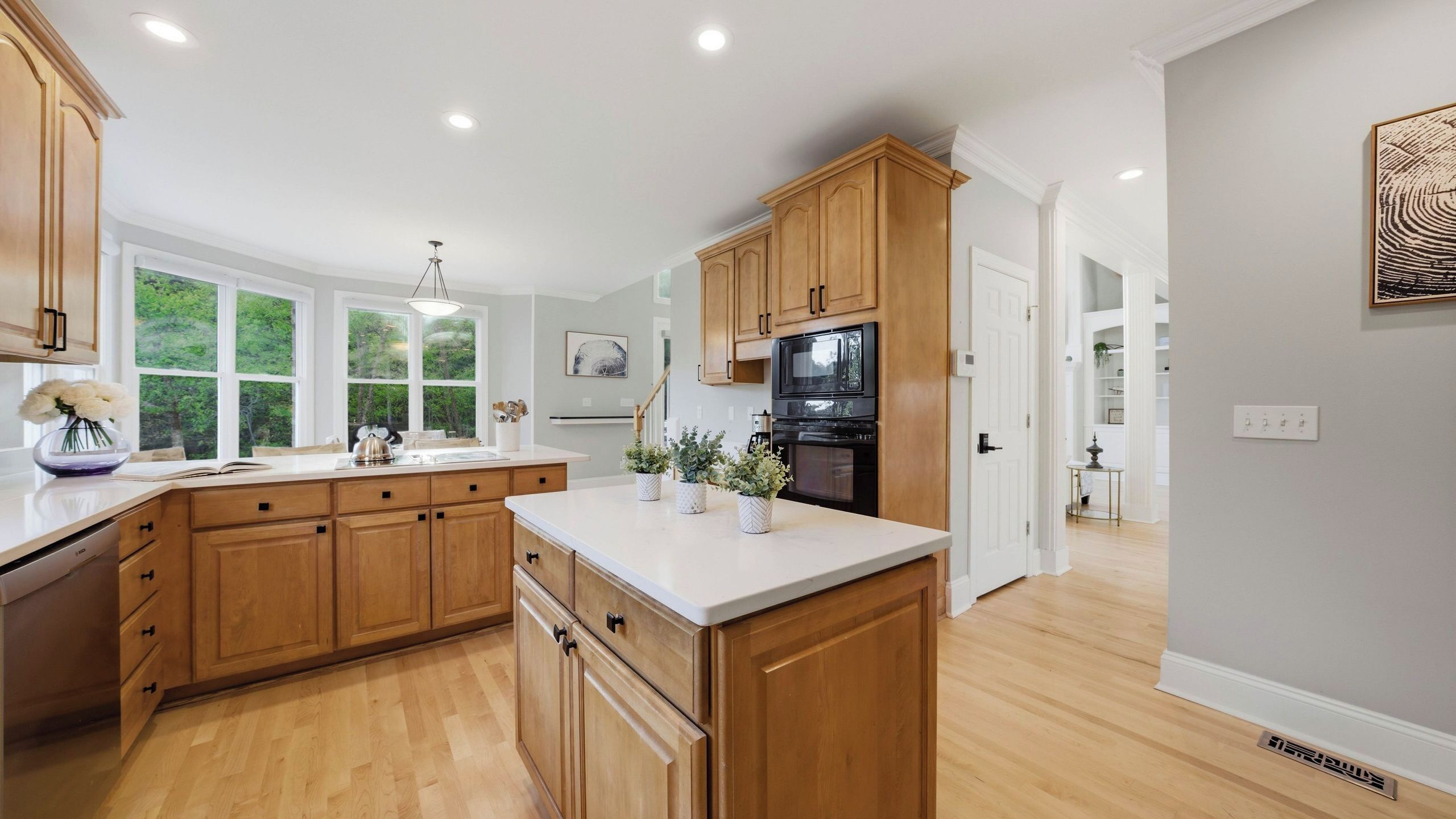 A spacious kitchen with wooden cabinets, a large island, and a view of greenery outside.