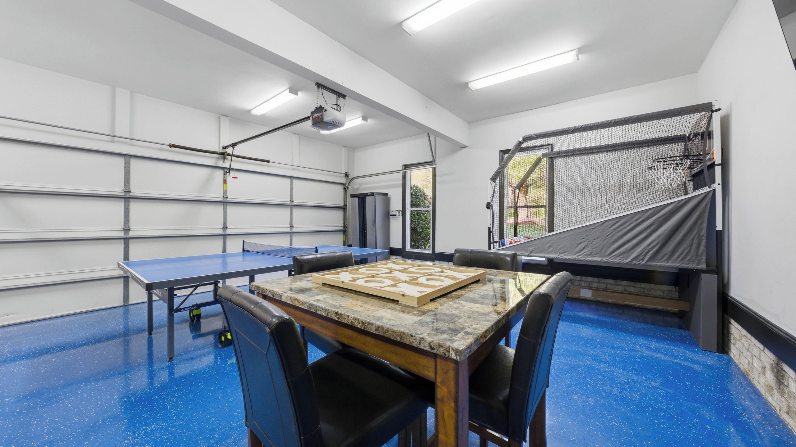 Ein Zimmer mit Tischtennisplatte, Kicker und einem großen Fenster.