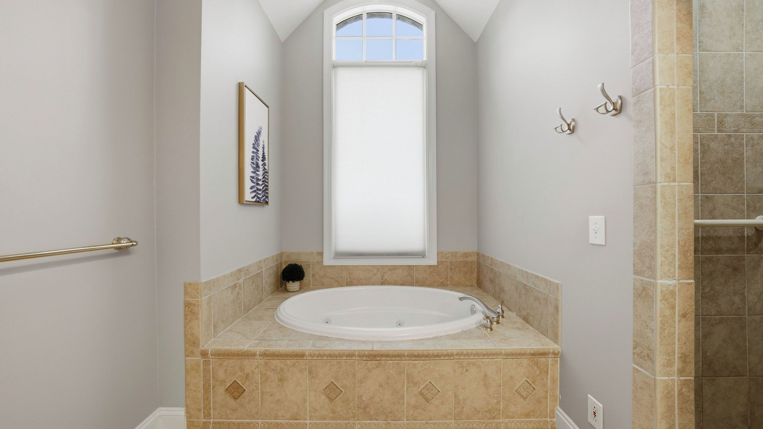 A bathroom with a bathtub, a window, a towel rack, and a shower area.
