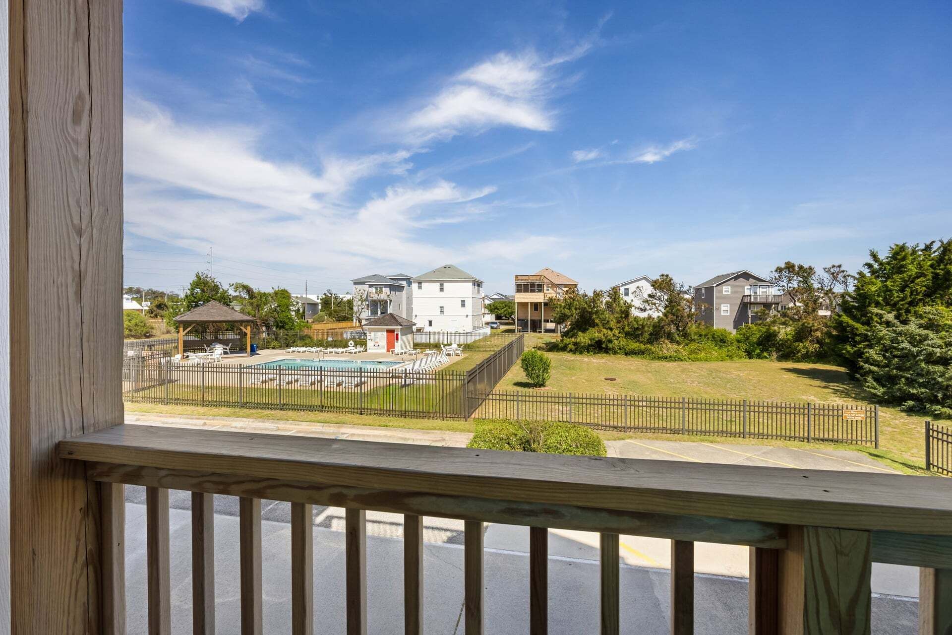 A residential area with a swimming pool, fenced yard, and houses with various architectural styles.