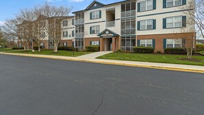 Um edifício de apartamentos com várias andares, fachada de tijolos, diversas varandas e céu limpo.