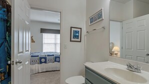 Uma casa de banho com lavatório, sanita e porta que dá para um quarto.